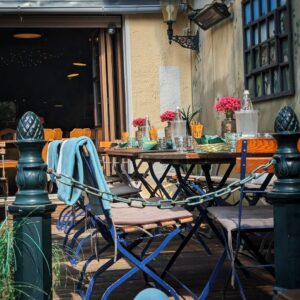 Sonnige Außenterrasse mit gedeckten Tischen, Stühlen und Blumendekoration im Wirtshaus Ausspann´