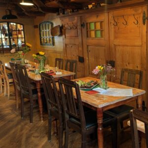 Gedeckte Holztische mit Blumendekoration im rustikalen Gastraum des Wirtshauses Ausspann´