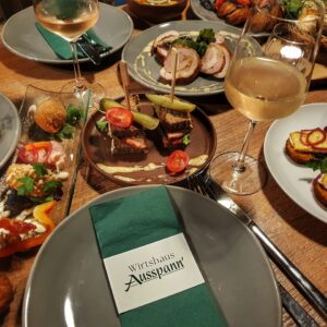 Auswahl verschiedener Wirtshaus-Tapas mit gefüllten Hähnchenbrustscheiben, Mini-Leberkäse-Sandwiches und Weißwein im Wirtshaus Ausspann´